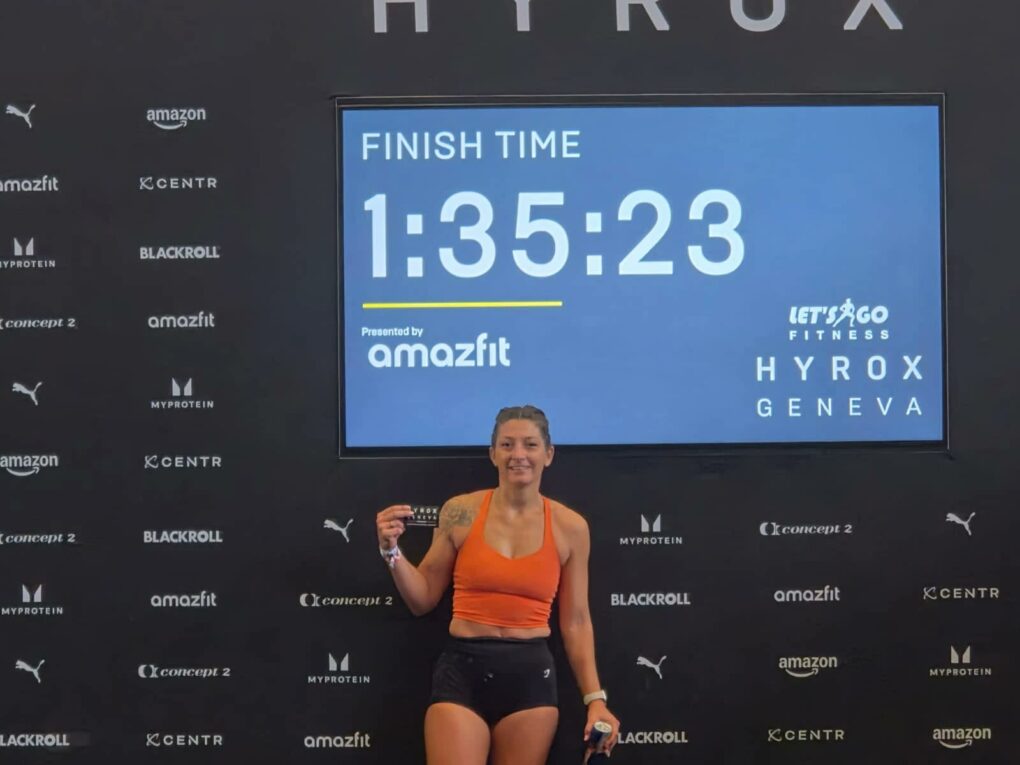 Stéphanie, adhérente du club SMLV, devant l'écran affichant son temps de 1 h 35 min 23 s à la fin du HYROX de Genève